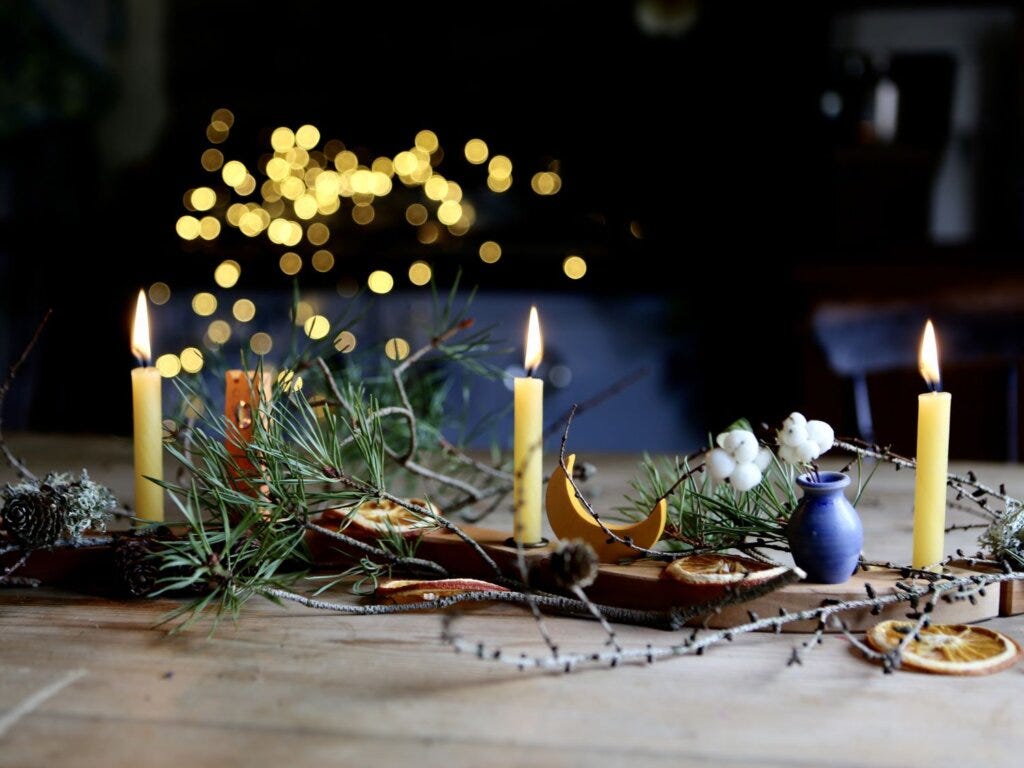 A 12 days of Yuletide table centrepiece with a wooden celebration ring, candles and evergreens A 12 days of Yuletide table centrepiece with a wooden celebration ring, candles and evergreens