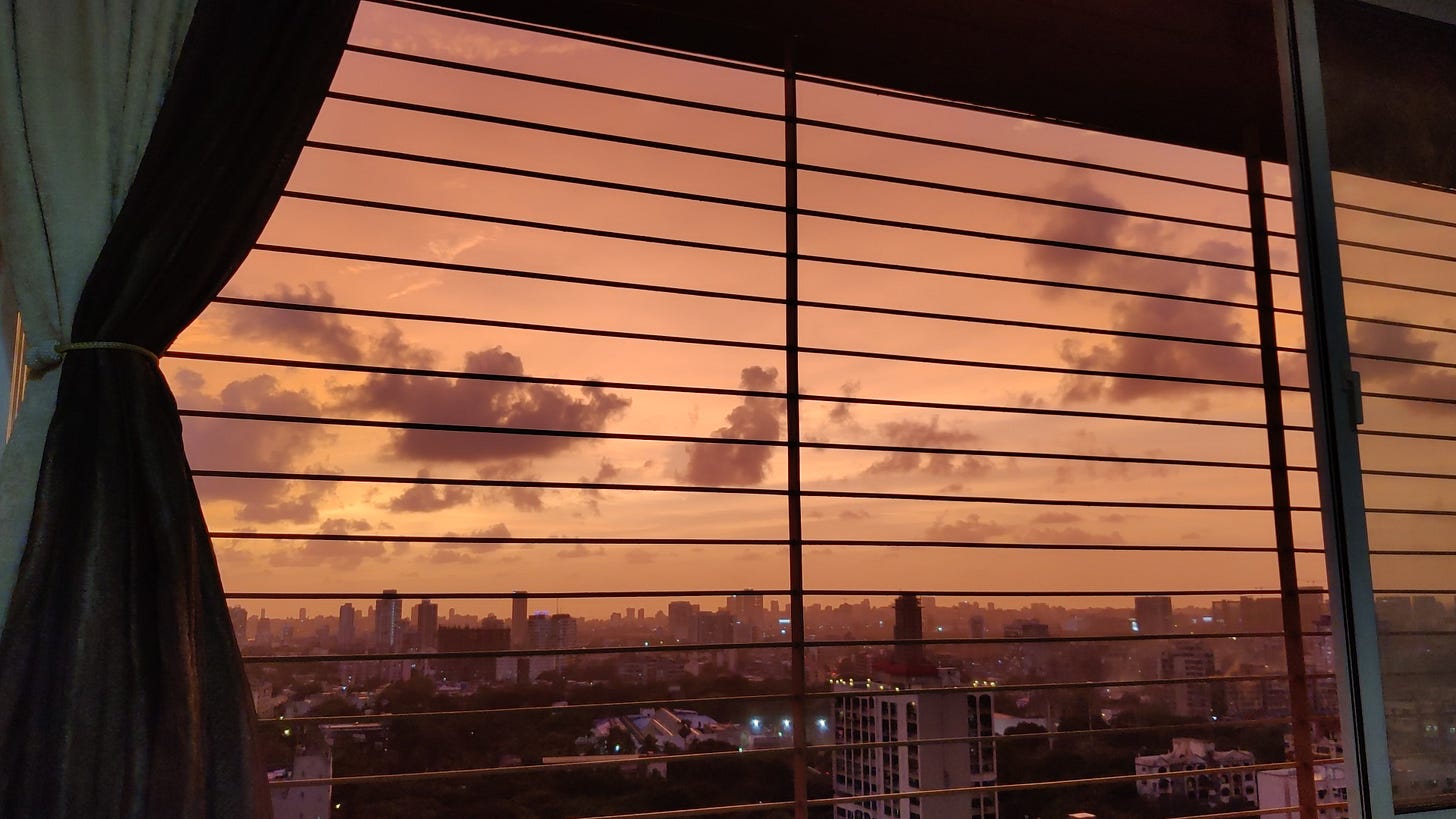 a pink, purple, orange sunset in Mumbai seen through a boxed window