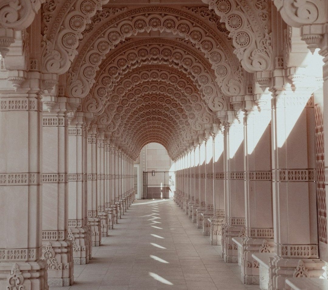A long hallway with arches and benches on both sides