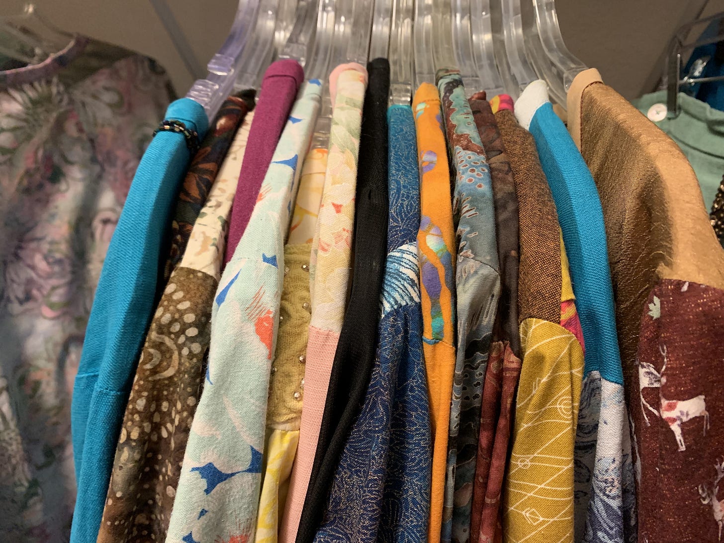 Row of colorful hand-sewn garments hanging on a clothing rack Row of colorful hand-sewn garments hanging on a clothing rack