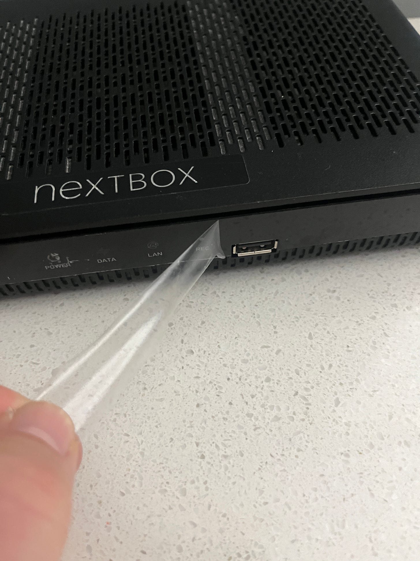 A layer of clear plastic adhesive film is peeled away from the front of an electonics box