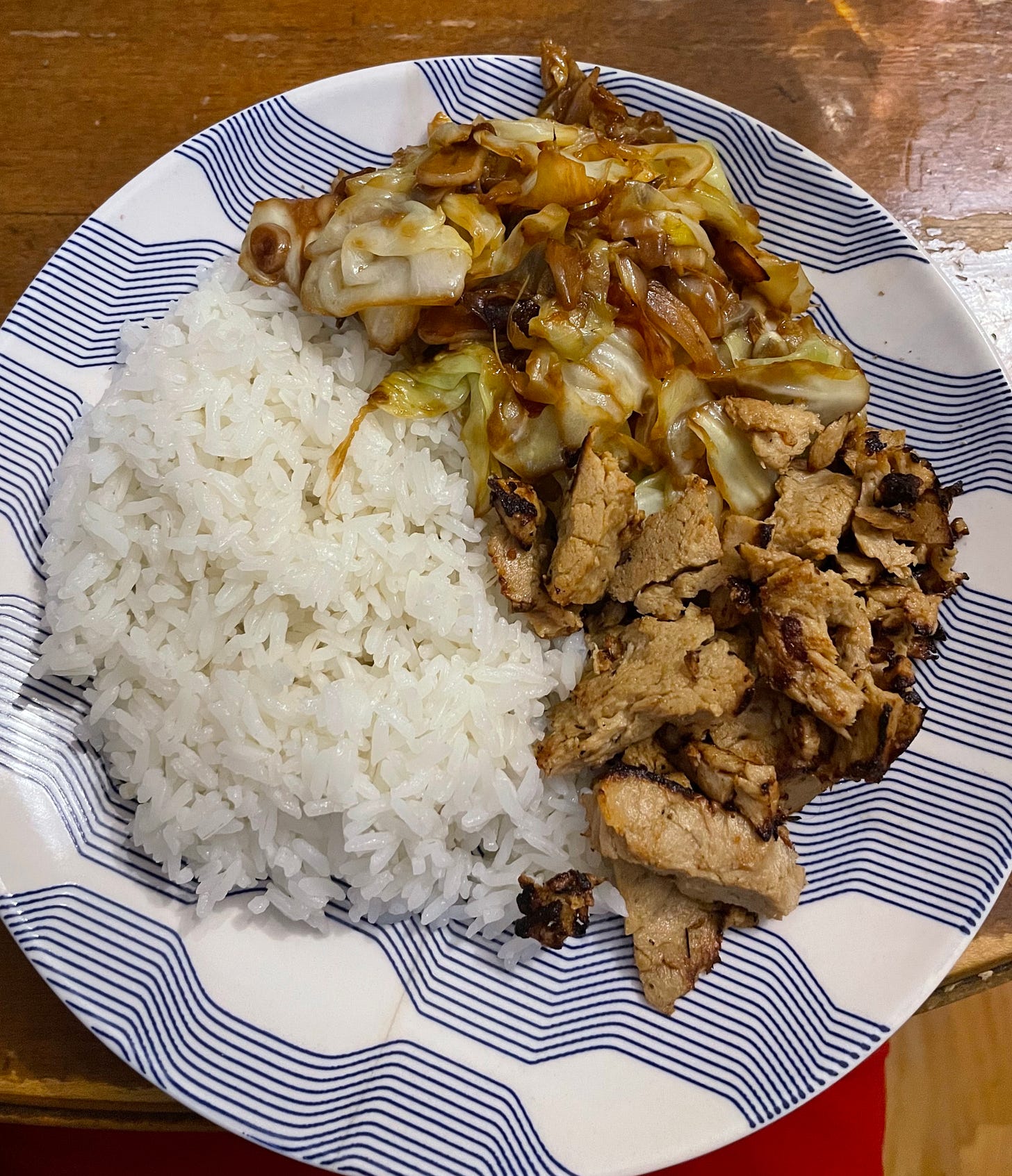 blue plate with rice, vegetarian chicken, and stir fried cabbage