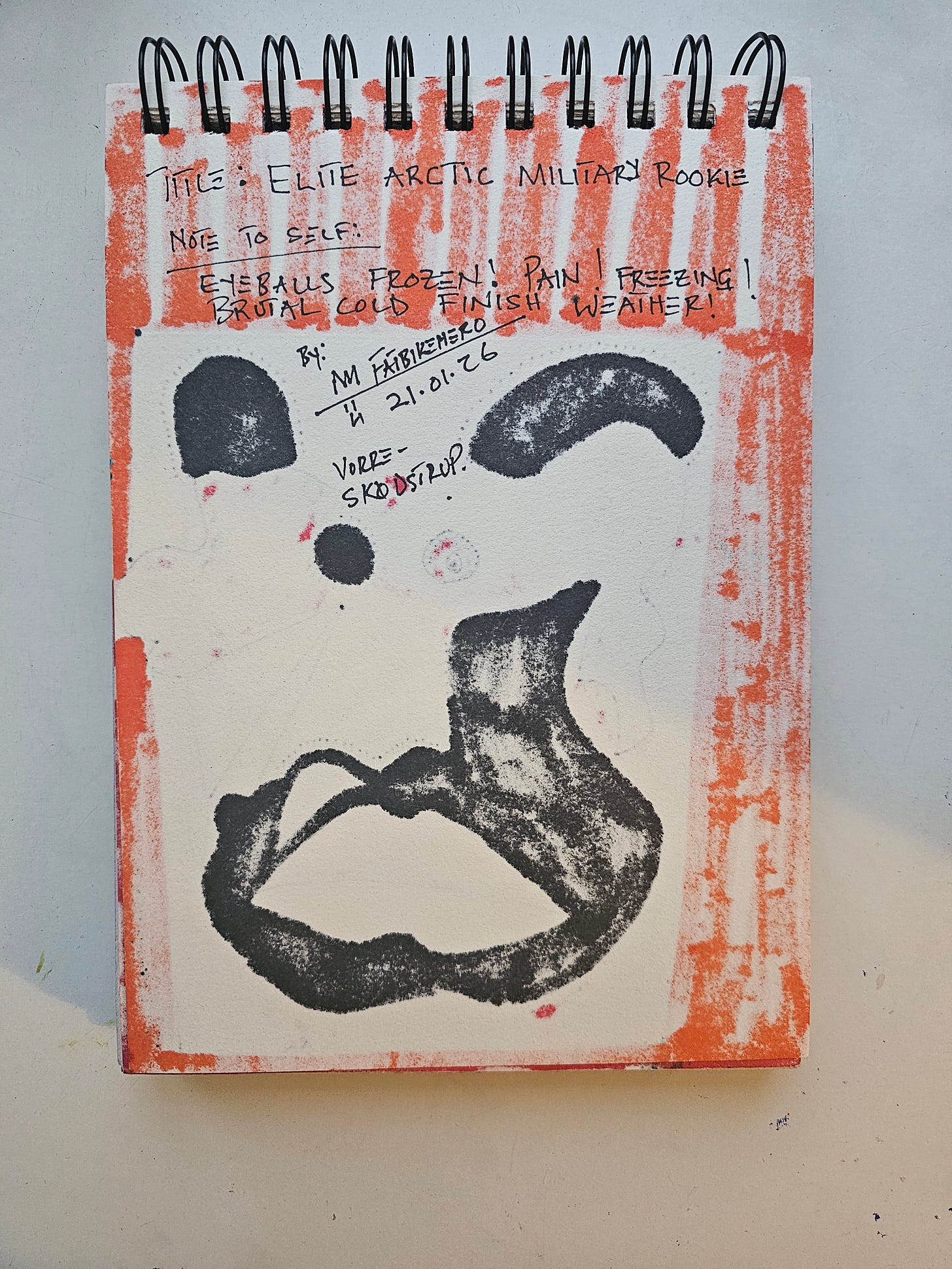 Alt Text: A sketchbook page containing handwritten notes and a sparse ink sketch. The text reads "TITLE: ELITE ARCTIC MILITARY ROOKIE" and "NOTE TO SELF: EYEBALLS FROZEN! PAIN! FREEZING! BRUTAL COLD FINISH WEATHER!". The sketch depicts three black abstract shapes. The page is bordered by orange marker stripes.