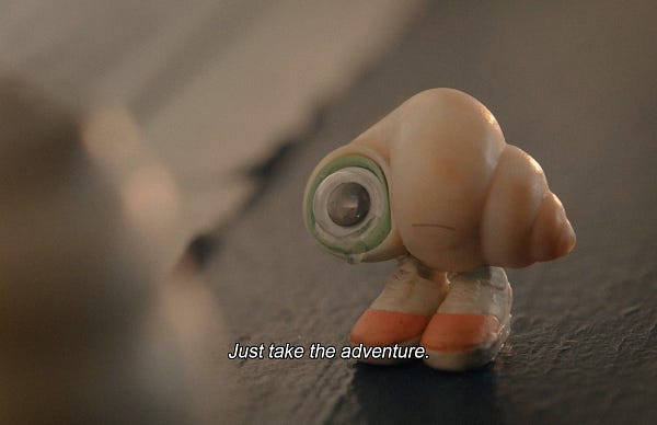 A film still from MARCEL THE SHELL WITH SHOES ON. The elderly shell continues to speak as the young shell weeps, "Just take the adventure."
