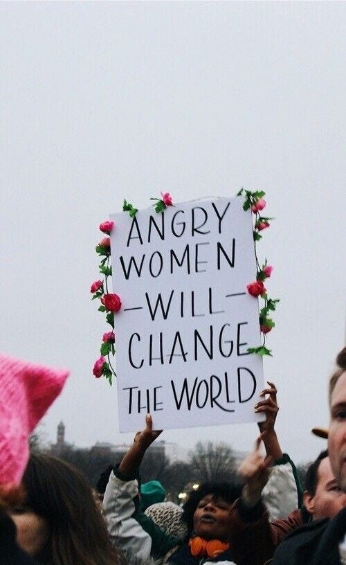 This may contain: a group of people holding up signs with flowers on them and one person wearing a pink hat