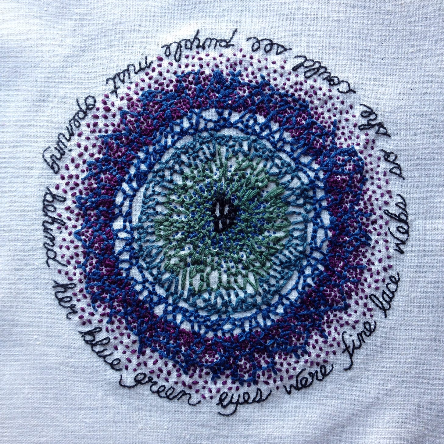 An embroidery of the venations of the eye stitched in blues, greens, and purples on bone coloured cloth. In a circle outlining the eye is a poem that can be read starting on any word: behind her blue green eyes were fine lace webs so she could see purple mist opening.