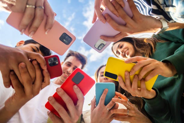 Young group of people using mobile phone device standing in circle outdoors Young group of people using mobile phone device standing together in circle outdoors. Millennial friends addicted to social media app, betting or playing video game on platform online. gen z stock pictures, royalty-free photos & images