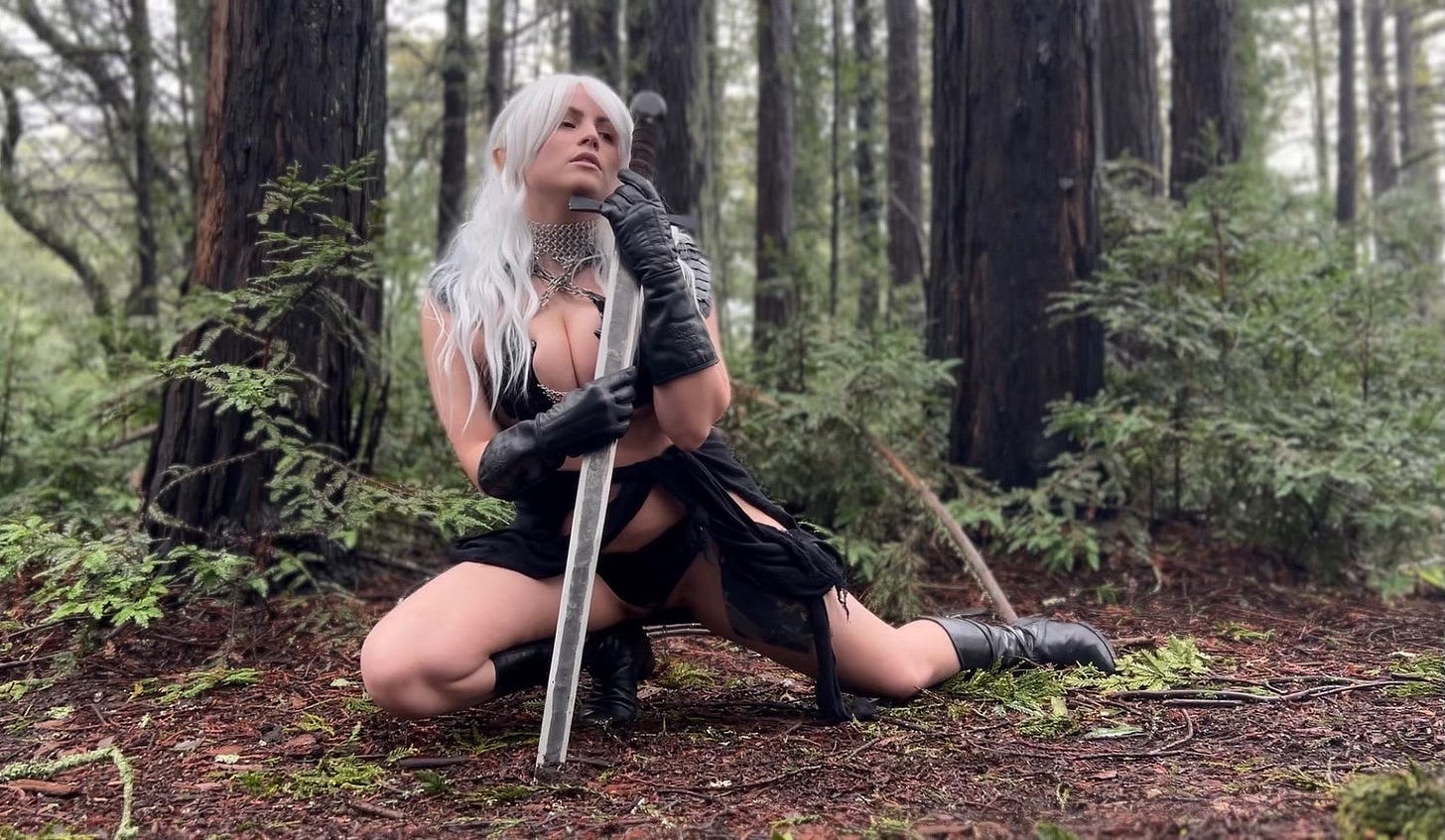 Photo of crossplay duplicating the pose from ELRIC AND THE SINKING CITY. In a forest setting, an elvish beauty crouches with one knee bent and the other leg extended, her weight resting on a a broad sword planted in the ground. Eyes closed, her expression focused emotion inward. Long white hair spills over her shoulder with a pinkish ear poking through the veil. She wears leather gloves that extend to her forearms. Likewise her boots rise to mid-calf. Her lower garment is in tatters. She wears a chainmail choker with a matching metal cinching tight her top, crossing in an X near her neck.