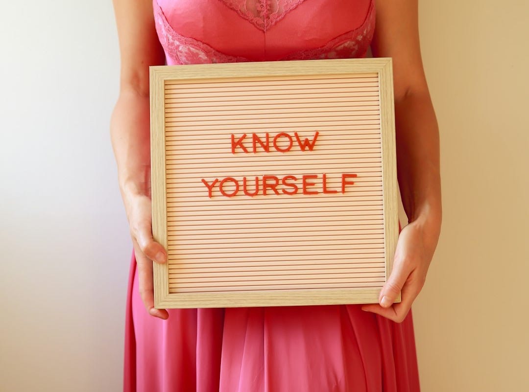 Woman holds sign that says "know yourself".