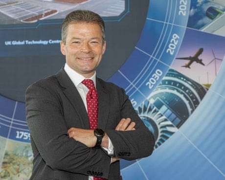 Peter Dilnot in a suit and tie with his arms folded, smiling