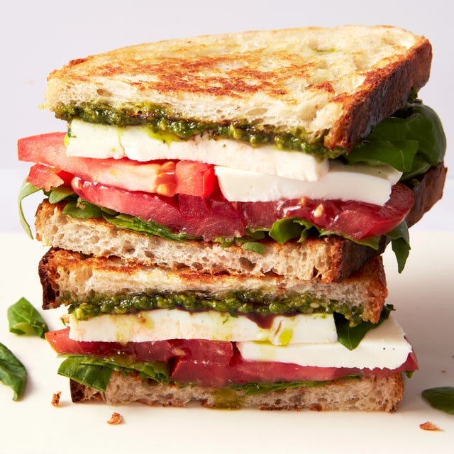 toasted bread layered with mozzarella, tomato slices, basil, arugula, pesto, and balsamic
