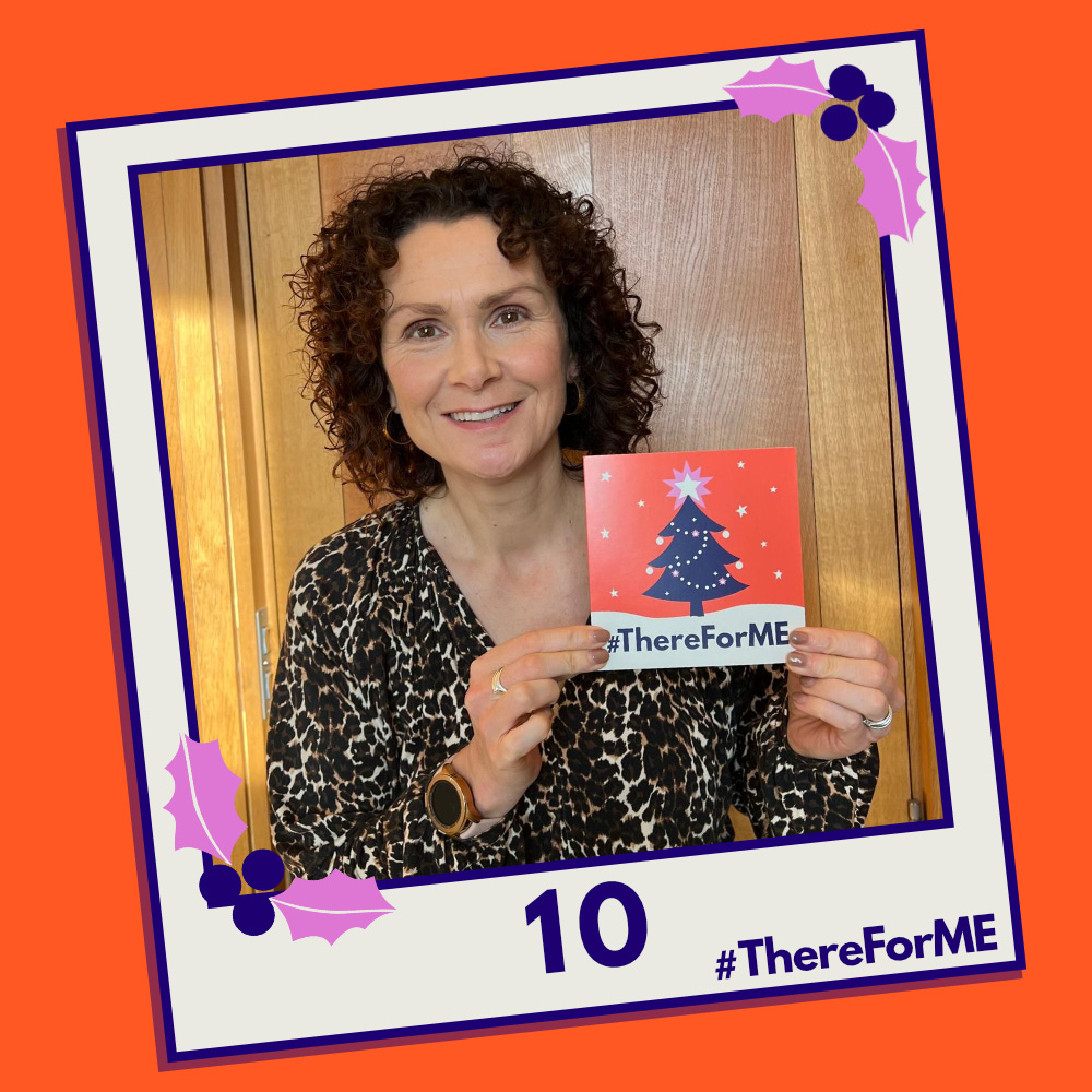 A pretend polaroid shows a smiling Wendy Chamberlain MP posing for a photo holding a #ThereForME Christmas card.   The image on the card shows the dark blue Christmas tree, decorated with sparkling fairy lights, baubles and a star on the top, in a snowy landscape against a starry backdrop. The design is in the #ThereForME colours.