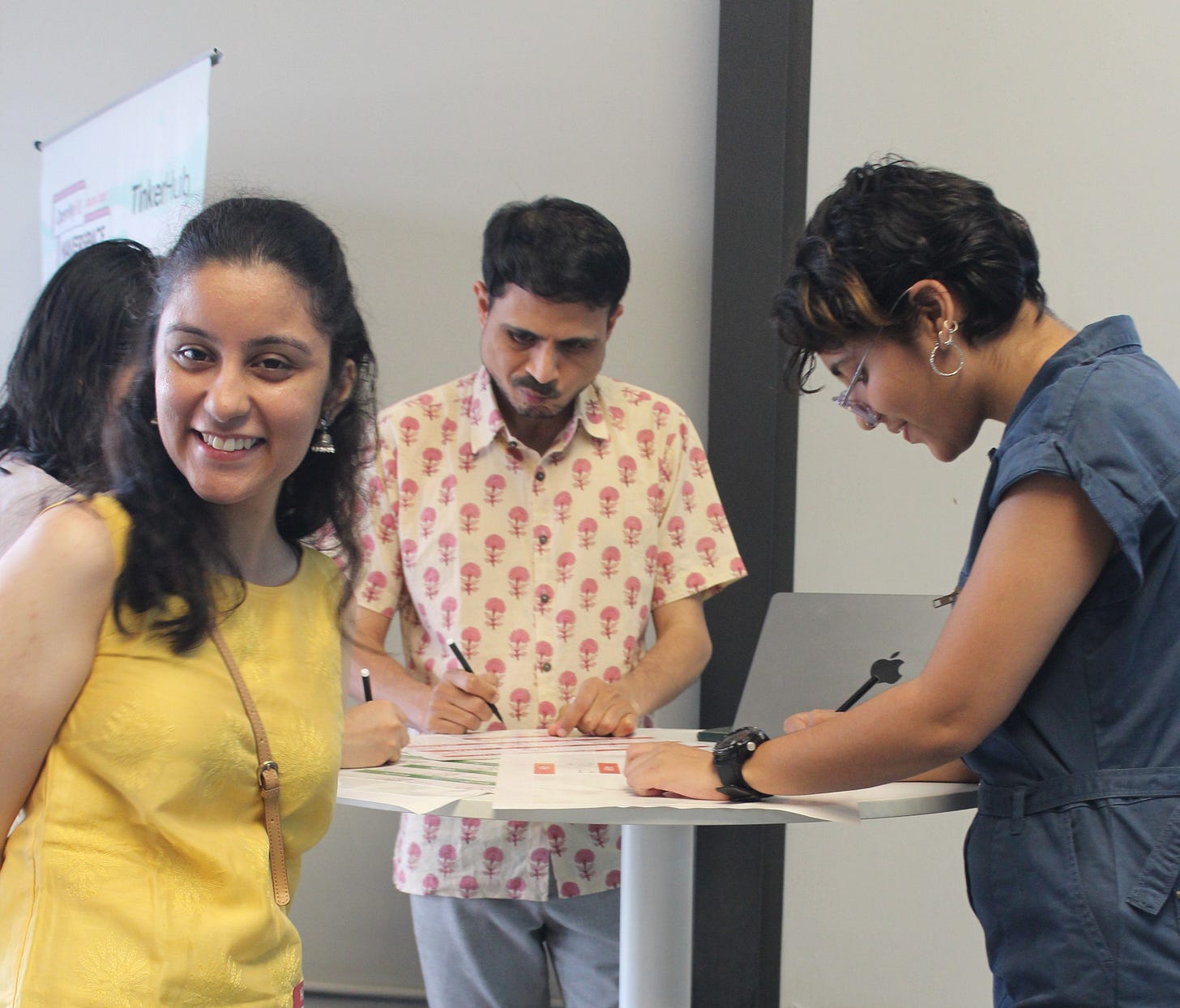 A group of people standing around a table, with one facing the camera and smiling