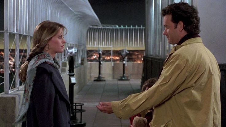 This may contain: a man and woman standing next to each other in front of a building at night