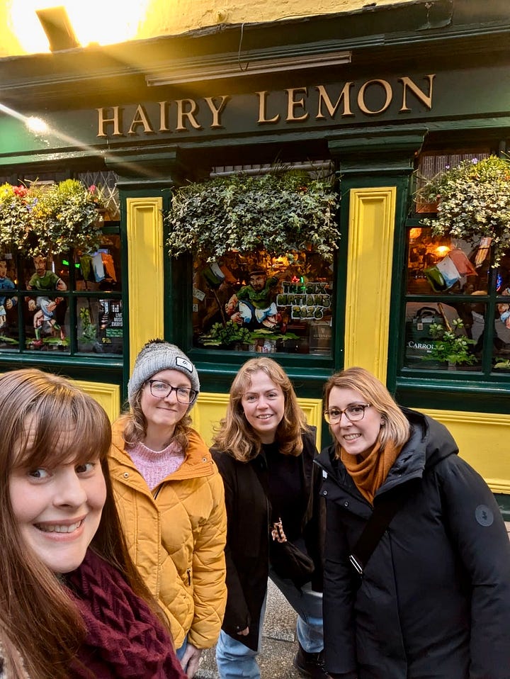 Two side-by-side photos of four women smiling outside Dublin pubs. In the first, they stand in front of the green and yellow exterior of The Hairy Lemon. In the second, they pose on cobbled streets in front of a Guinness sign, laughing and gesturing enthusiastically at the camera.