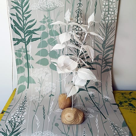 Brightly coloured paper flowers photographed against a backdrop of elegant, hedgerow inspired wallpapers.