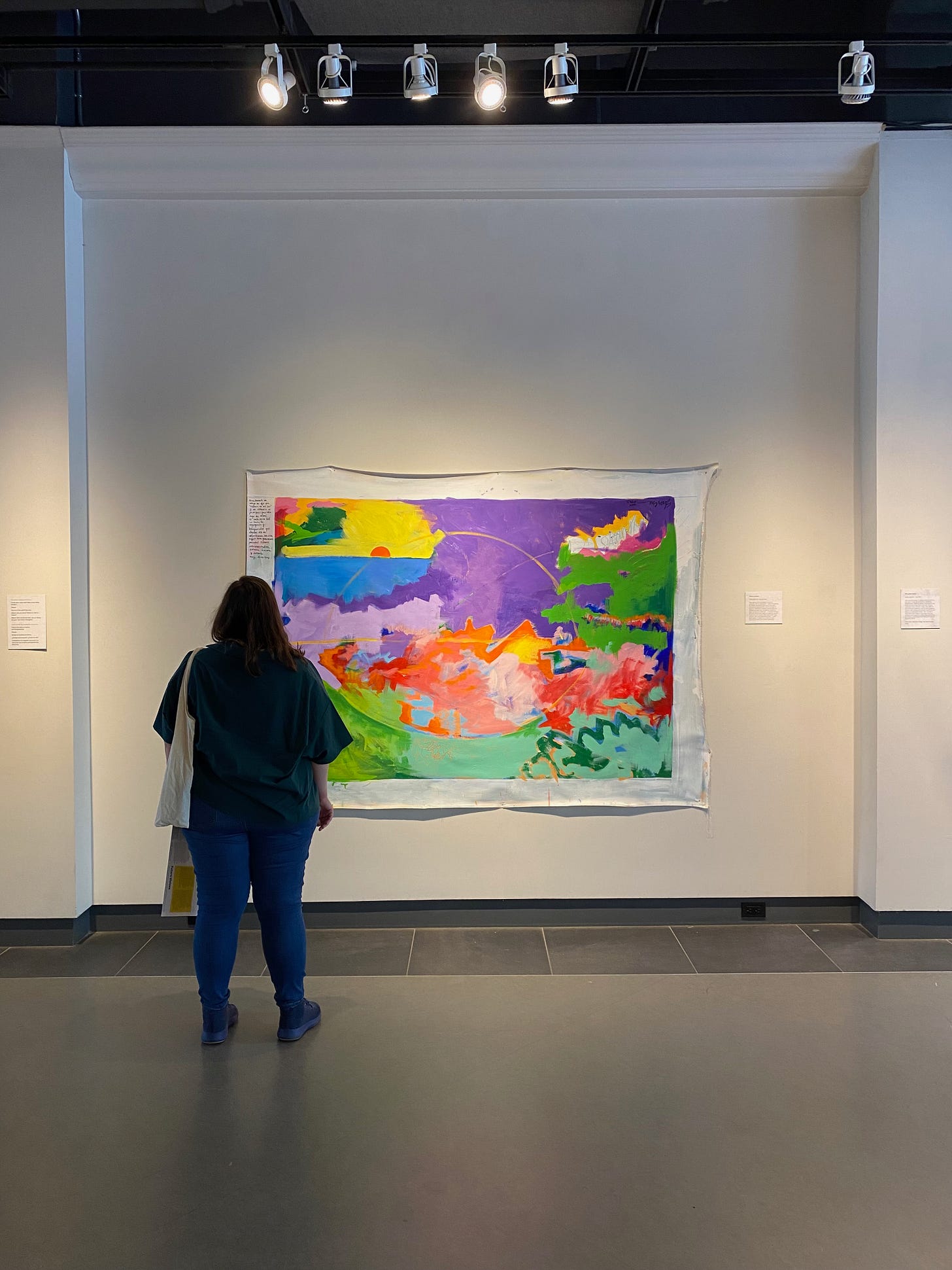 A person looking at a large colorful painting on the wall.