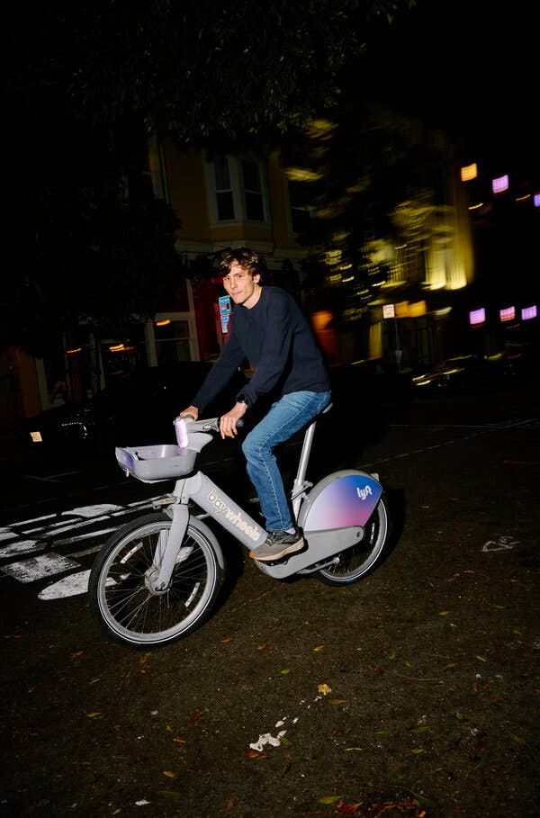 Riley Walz rides a Lyft bike, which he often takes to and from work, at night on a San Francisco street.