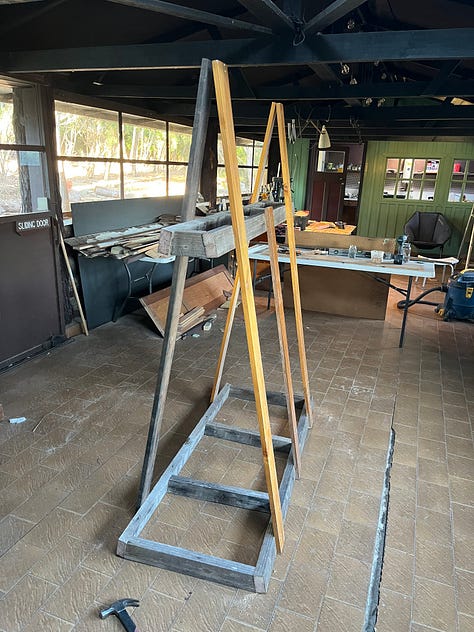 A wooden frame for storing and painitng wooden panels and tools and a series of coffee can lanterns in the process of being restored.