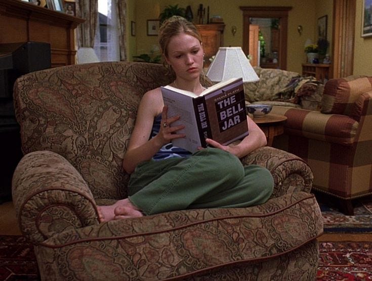 This may contain: a woman sitting in a chair reading a book