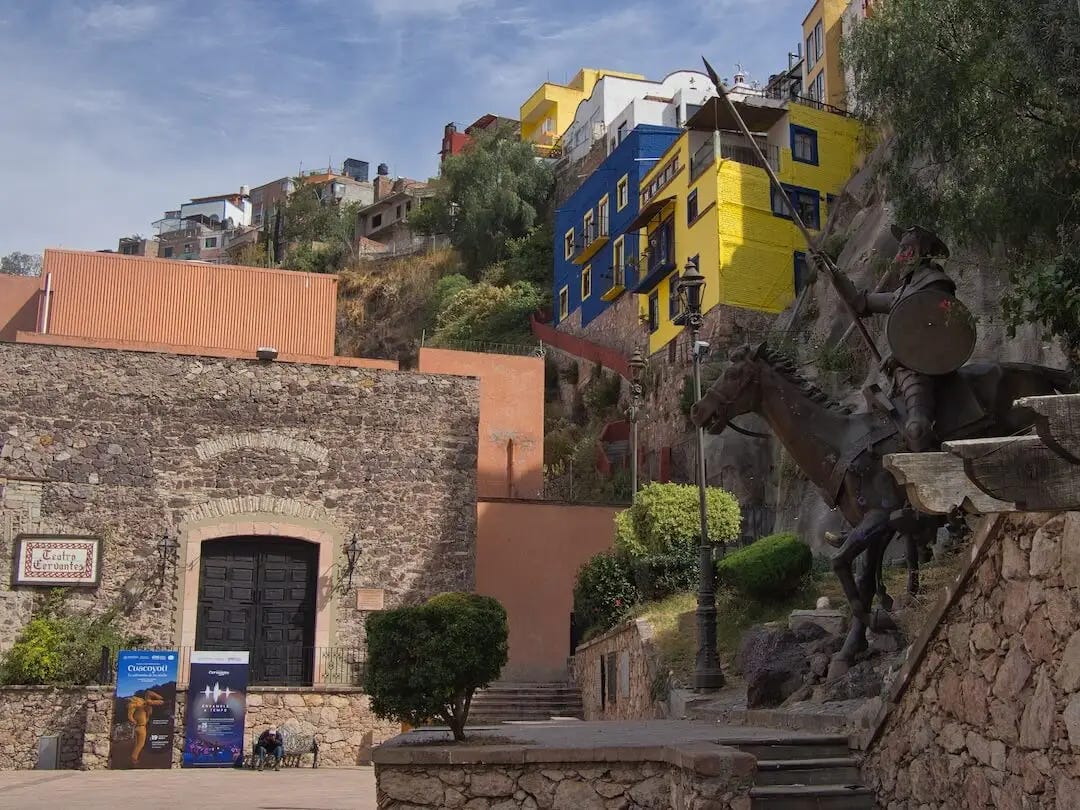  Two statues of figures on horseback beside a theatre