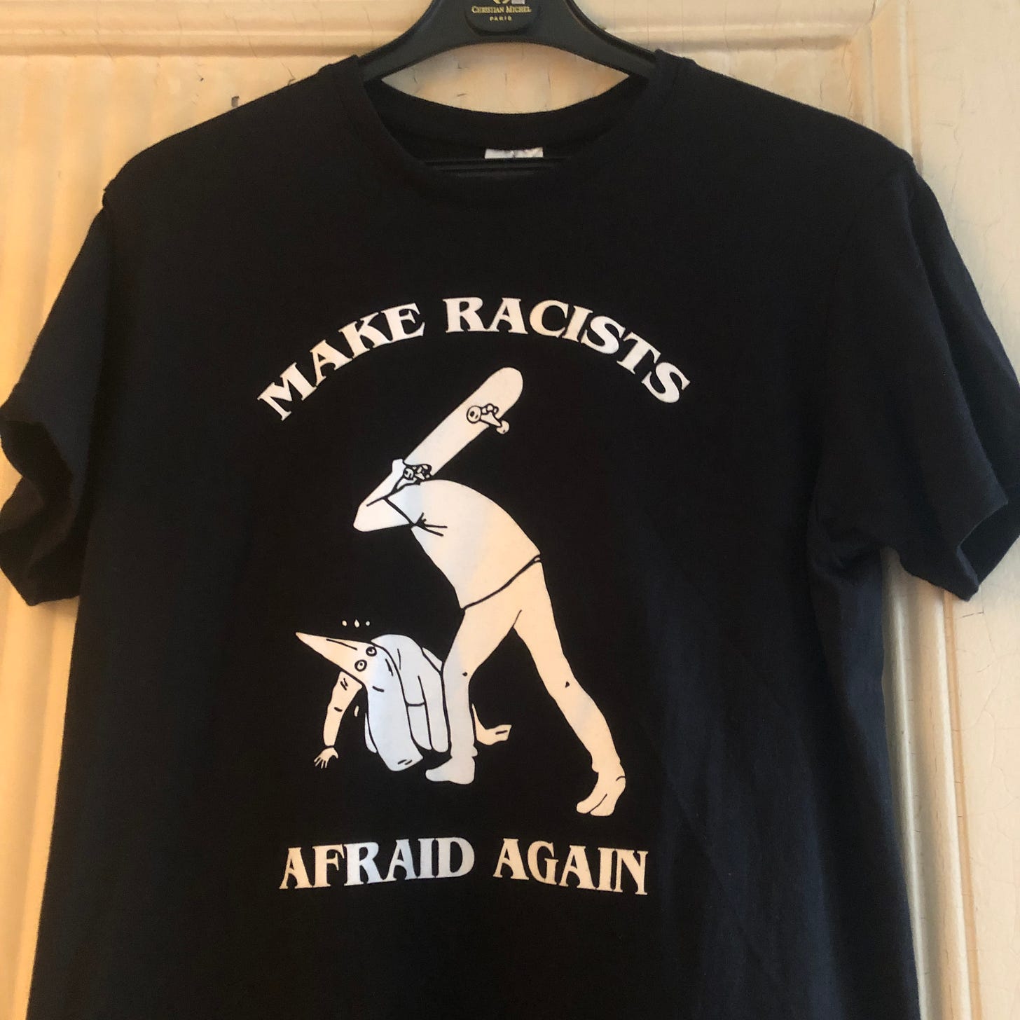Mon tee-shirt noir avec en blanc le slogan "Make racists afraid again" et le dessin d'une personne menaçant d'un coup de skateboard un membre du KKK