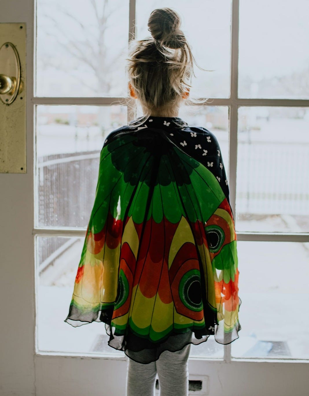 woman in green orange and yellow dress standing near window