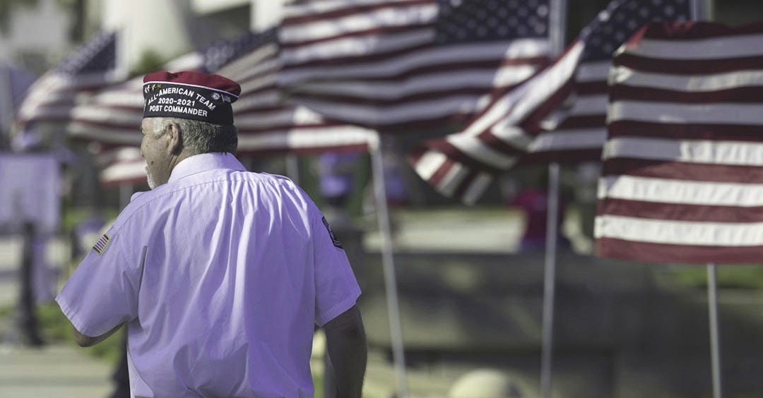 a man standing in front of a row of american flags