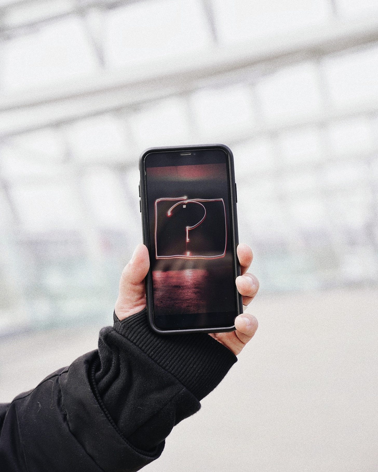 Hand holding up an iPhone, screen facing the viewer. On the screen is a hand-drawn question mark. Hand holding up an iPhone, screen facing the viewer. On the screen is a hand-drawn question mark.