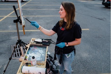 A person painting on a canvas

Description automatically generated