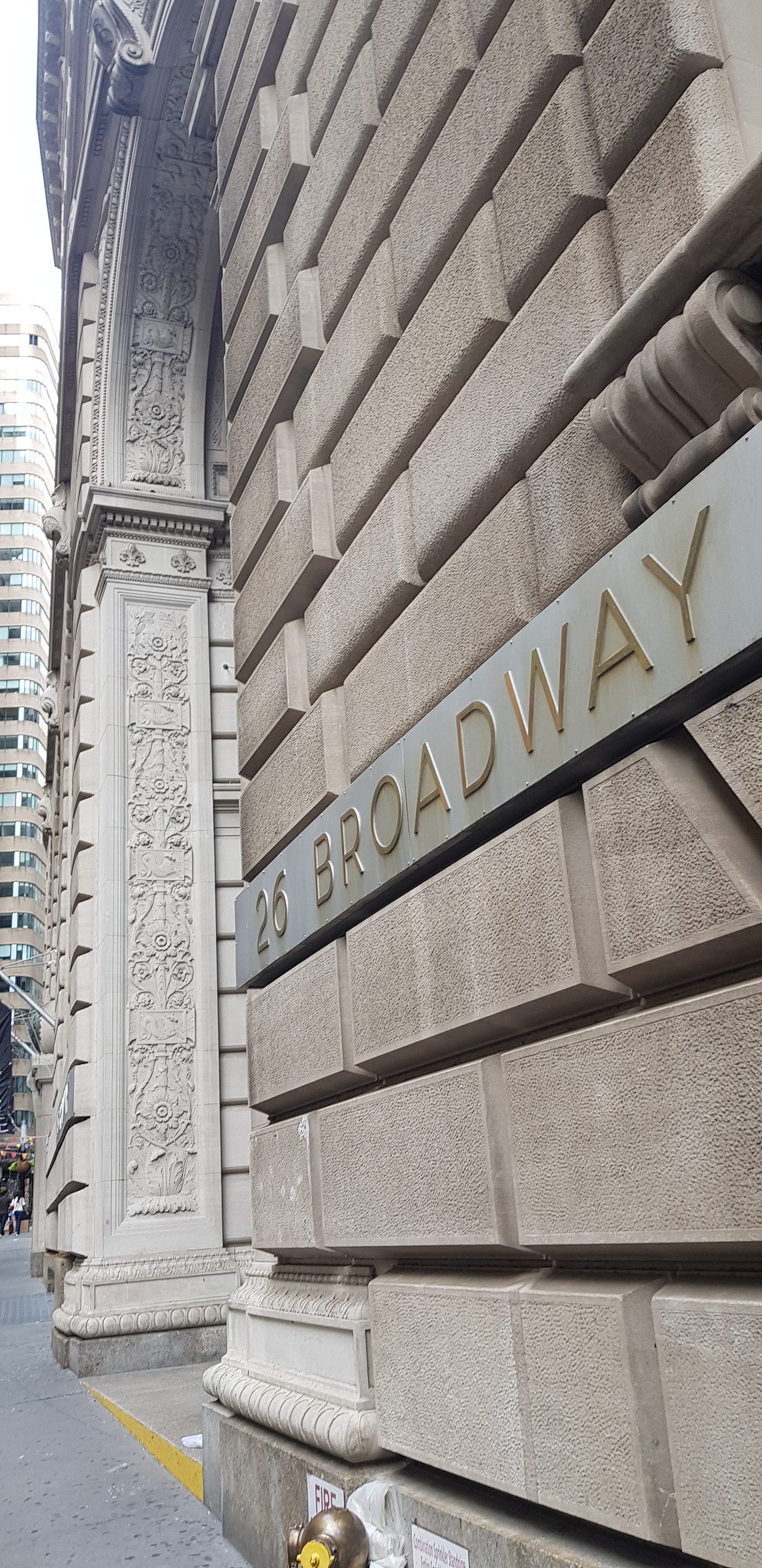 仰望石造建築雕飾門廊,門楣刻著 26 Broadway 仰望石造建築雕飾門廊,門楣刻著 26 Broadway
