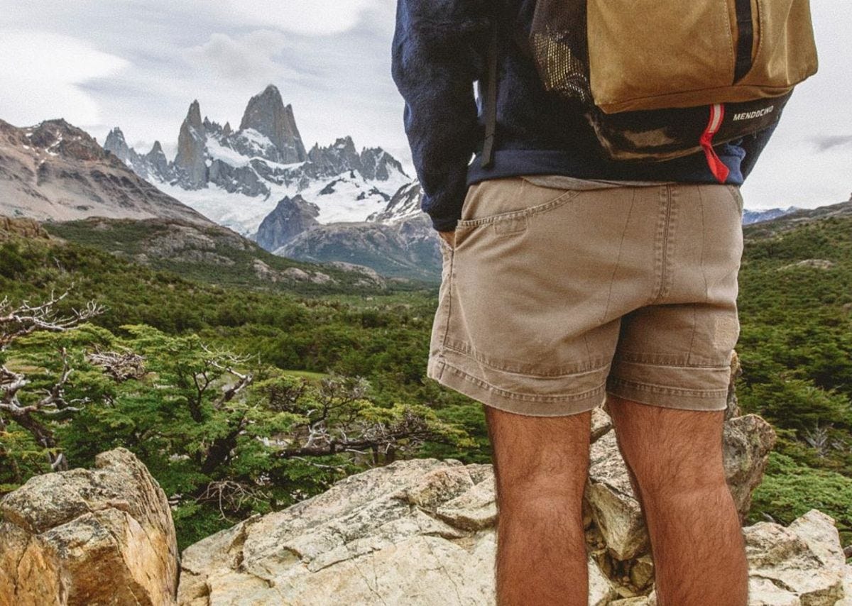 a man wearing patagonia stand up shorts stands in front of mount fitz roy in patagonia south america