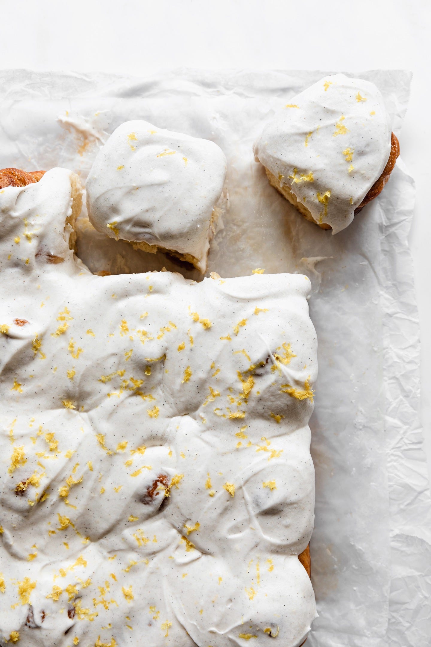 Vegan lemon cardamom sweet rolls on parchment on a white counter