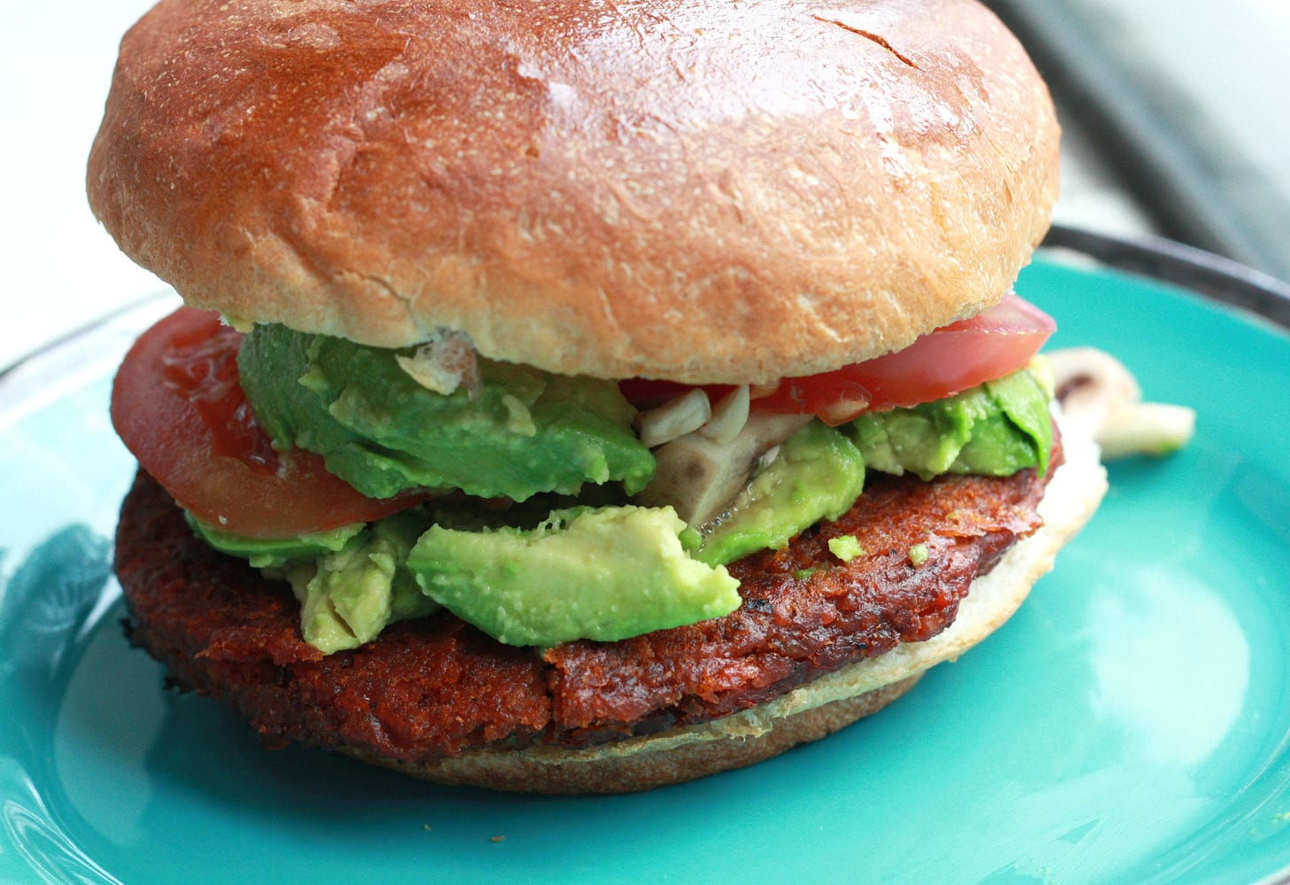 vegan burger on plate with avocado and tomatoe vegan burger on plate with avocado and tomatoe