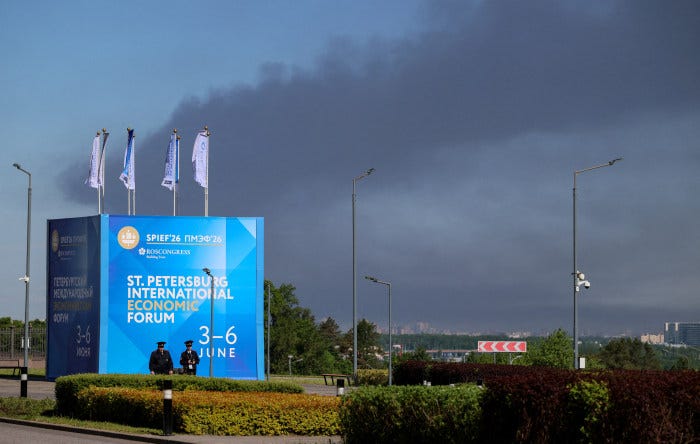 Police officers stand in front of a banner for the St. Petersburg International Economic Forum as heavy smoke billows in the background. Police officers stand in front of a banner for the St. Petersburg International Economic Forum as heavy smoke billows in the background.