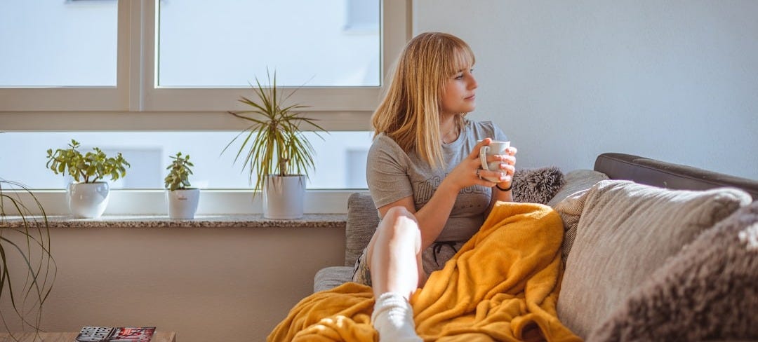 a woman sitting on a couch holding a glass of water a woman sitting on a couch holding a glass of water