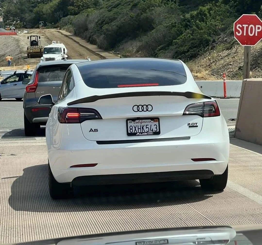 Rear view of a Tesla Model 3 that has had all Tesla badging removed and replaced with the Audi 'rings' logo and model badges for an Audi A5 with 2-liter turbocharged engine. Rear view of a Tesla Model 3 that has had all Tesla badging removed and replaced with the Audi 'rings' logo and model badges for an Audi A5 with 2-liter turbocharged engine.