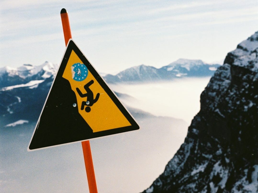 Warning sign for falling hazard on snowy mountain Warning sign for falling hazard on snowy mountain