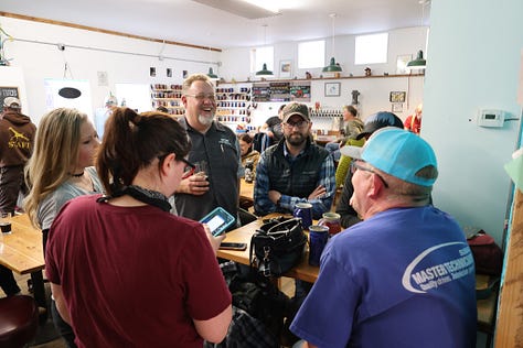 People drinking beer sitting down and standing up with frogs and toads in the background