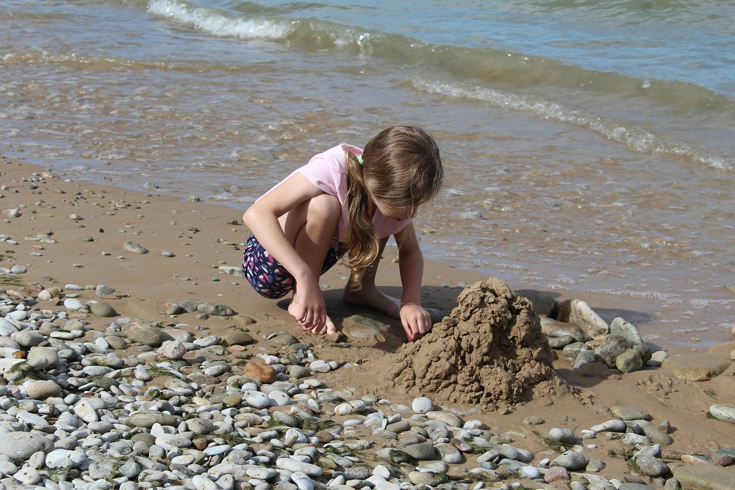 Girl Squatting and Playing on Beach · Free Stock Photo