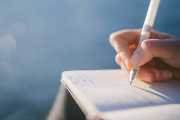 Young woman relaxes by lakeshore in the morning She writes in journal on lakeside pier, Lake Lugano below a writer thinking stock pictures, royalty-free photos & images Young woman relaxes by lakeshore in the morning She writes in journal on lakeside pier, Lake Lugano below a writer thinking stock pictures, royalty-free photos & images