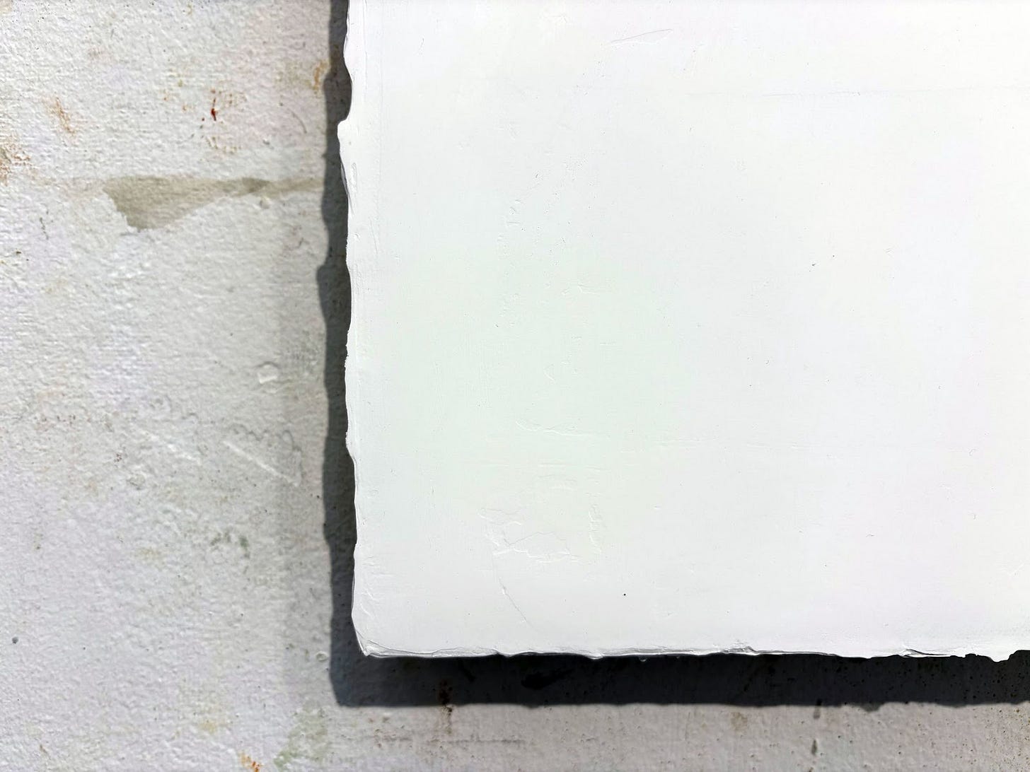 a close up image of the bottom corner edge of the painting surface which shows how the molding paste has built up on the edges of the canvas, creating an uneve surface.