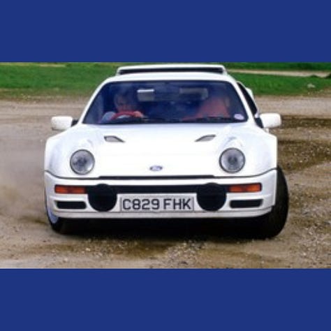 The RS200 without any livery or police markings being driven around a test track and in a garage next to a rally car.