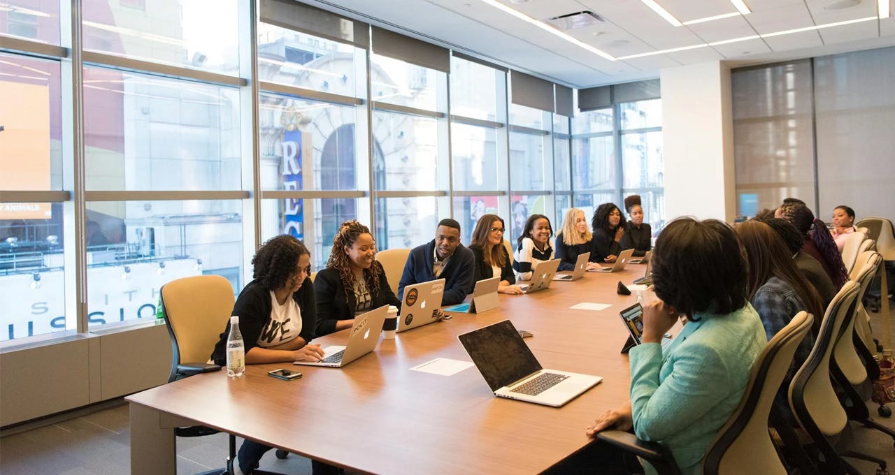 People sitting around a meeting table with laptops. People sitting around a meeting table with laptops.
