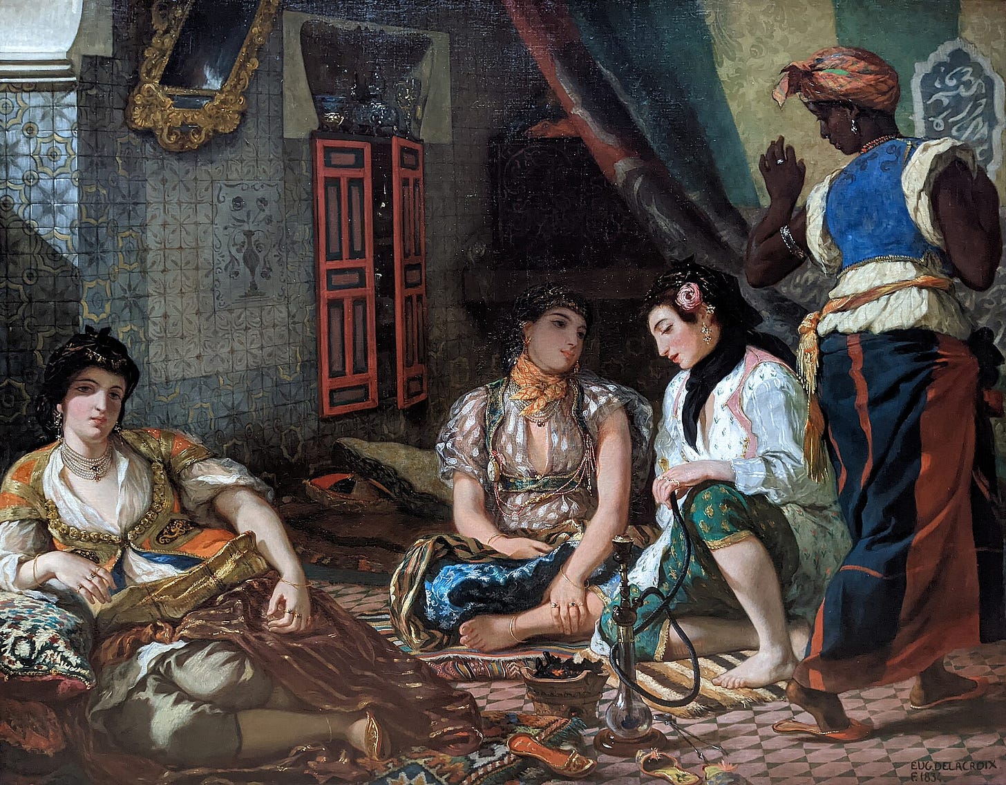 Three women in embroidered silks sit on carpets and cushions in a dim tiled interior beside a water pipe, while a Black servant turns away to lift a curtain. Three women in embroidered silks sit on carpets and cushions in a dim tiled interior beside a water pipe, while a Black servant turns away to lift a curtain.