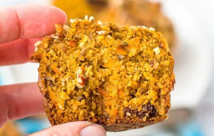 A hand holding a cut morning glory muffin. A hand holding a cut morning glory muffin.