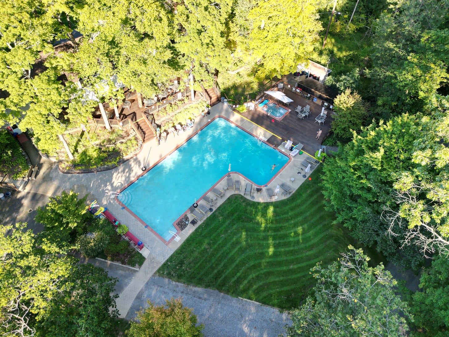 An aerial view of the Sky Farm common area featuring a pool and a lodge and a large grass lawn. An aerial view of the Sky Farm common area featuring a pool and a lodge and a large grass lawn.