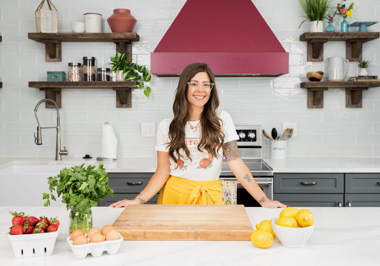 Kris Dovbniak, standing in a kitchen wearing a yellow skirt and white tee shirt Kris Dovbniak, standing in a kitchen wearing a yellow skirt and white tee shirt