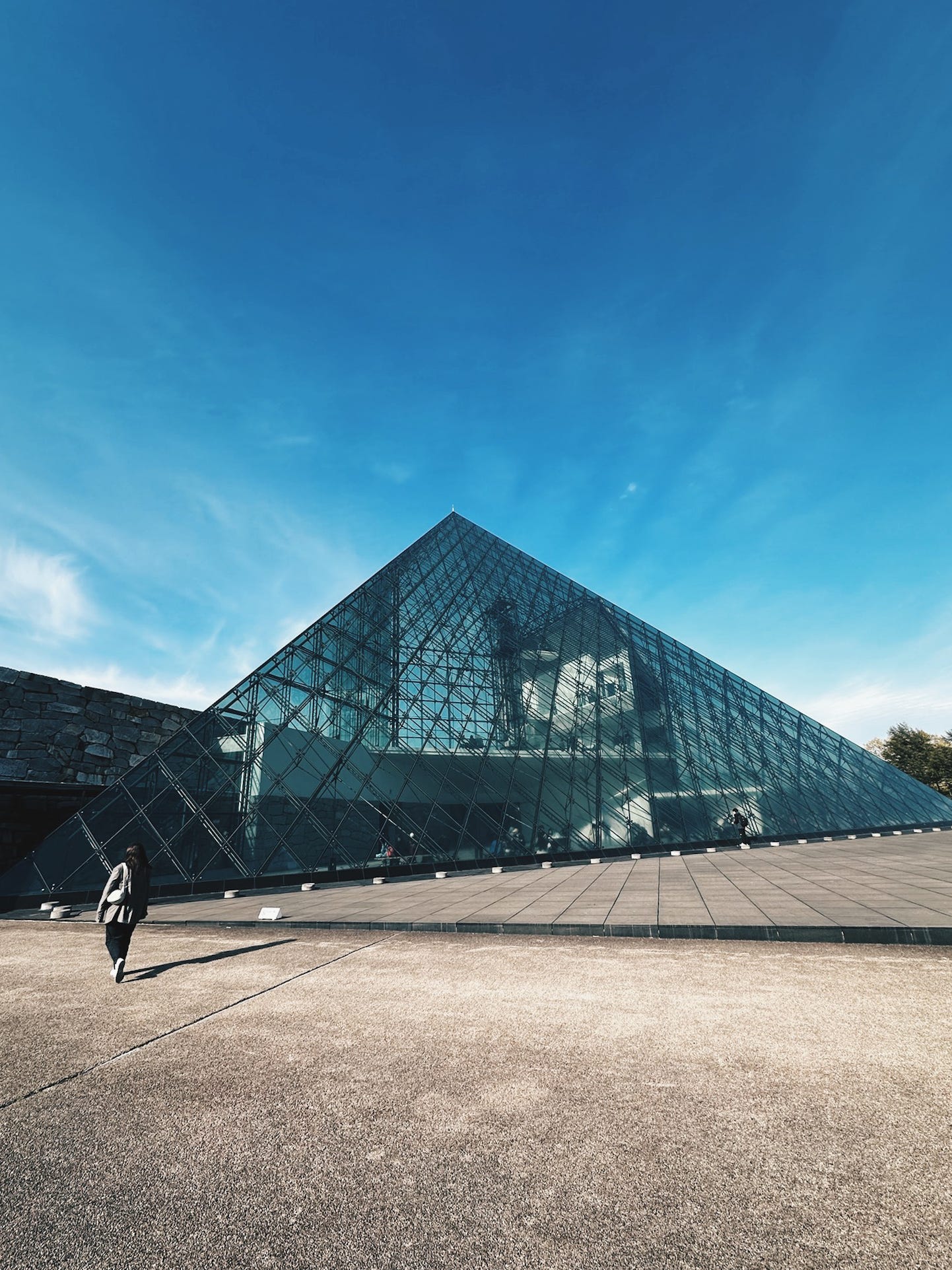 Isamu Noguchi's glass pyramid Hidamari rising from the green landscape of Moerenuma Park in Sapporo against a deep blue sky Isamu Noguchi's glass pyramid Hidamari rising from the green landscape of Moerenuma Park in Sapporo against a deep blue sky