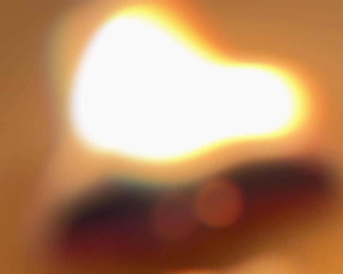 A soft, blurred image of a candle flame glowing warmly in the dark, symbolizing quiet strength, grief, and hope in the midst of suffering.